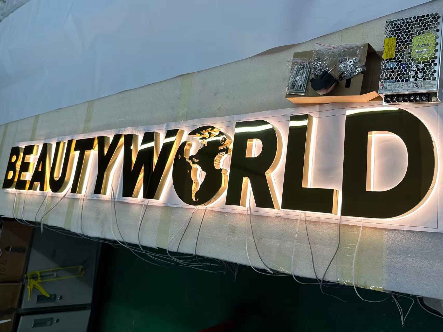 Technical setup of halo-lit custom led signs with mirror gold finish and professional power supply units.