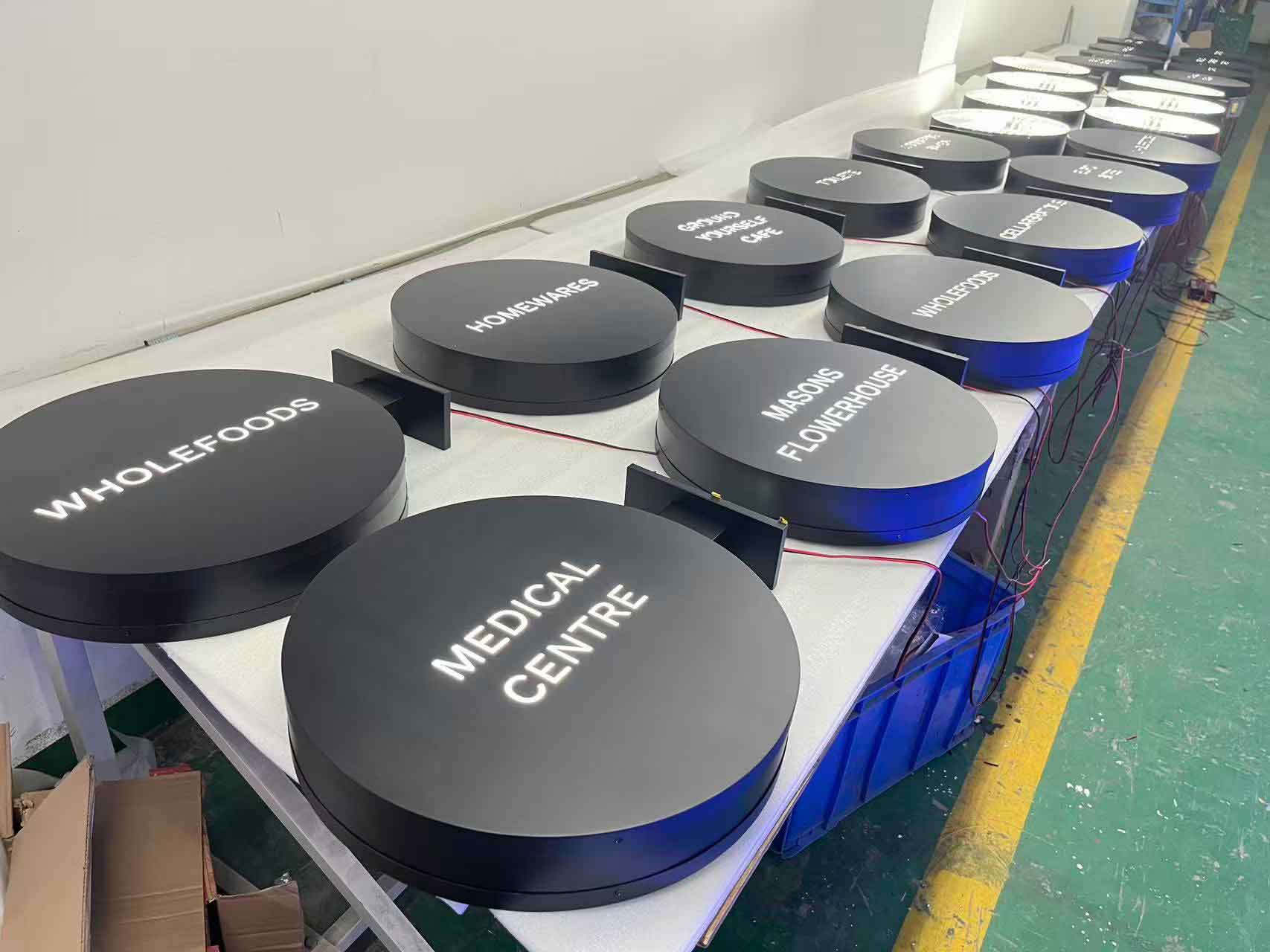 A row of premium circular **custom led signs** for medical centers and retail stores awaiting final quality inspection.