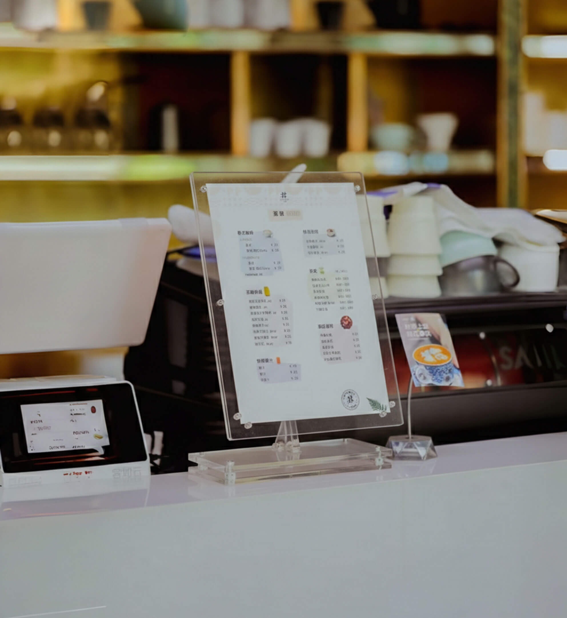 A high-transparency acrylic menu holder placed on a cafe counter, featuring a minimalist base and displaying a clear price list.
