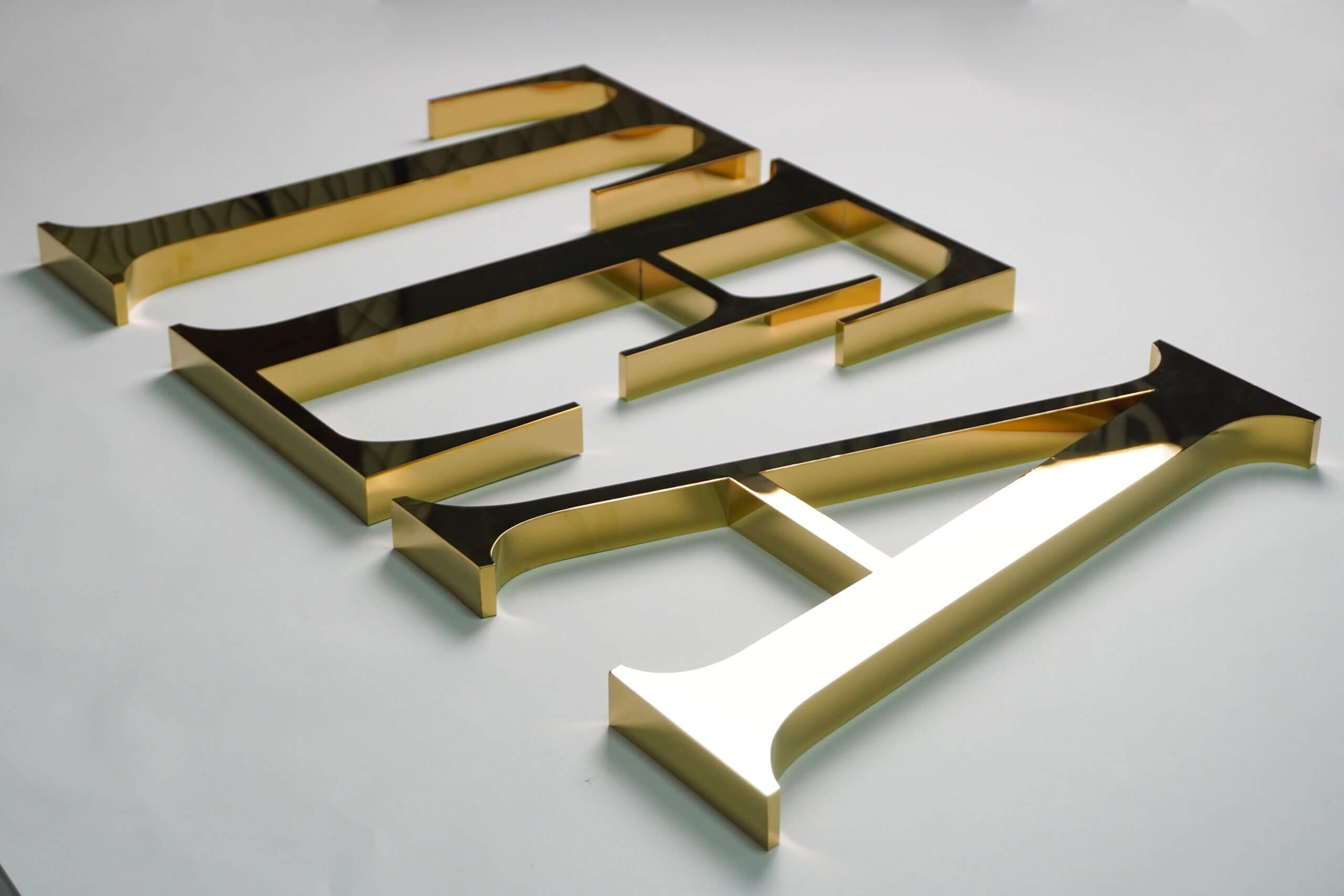 Gold mirror-finish stainless steel flat letters "IDEA" with a high-polished reflective surface and precision-cut edges.
