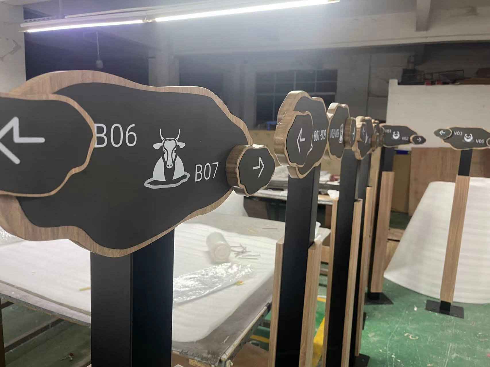 Elegant floor-standing wayfinding pylon in The Dubai Mall, featuring high-contrast bilingual directions and premium metallic finish for luxury retail environments.