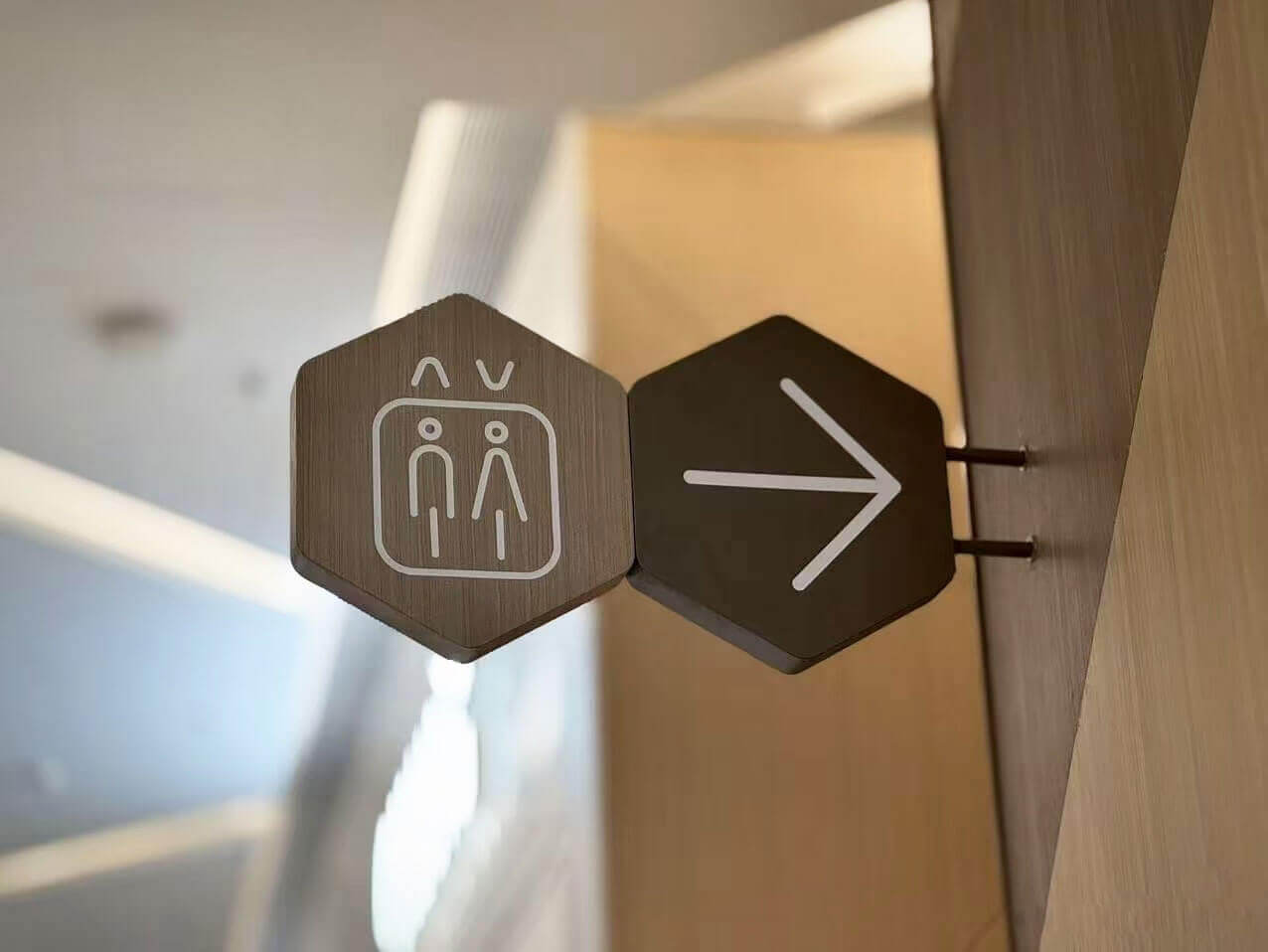 Modern hexagonal wooden directional sign for elevators.