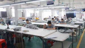 Skilled workers assembling custom signage products in a professional manufacturing workshop, including illuminated signs, channel letters, and commercial signage components.