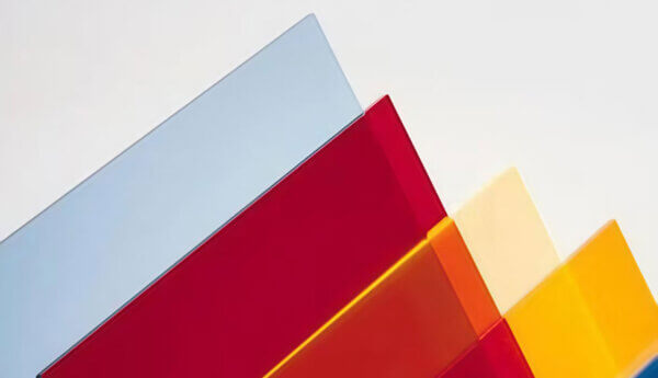 A stack of high-transmittance acrylic panels in various vibrant colors, showcasing uniform light diffusion and custom baked paint finishes for outdoor signage.